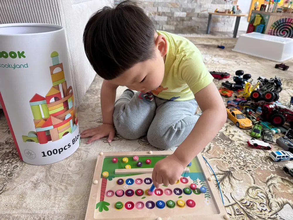 Child engaging in early literacy with magnetic alphabet maze at Kido Heaven preschool"
