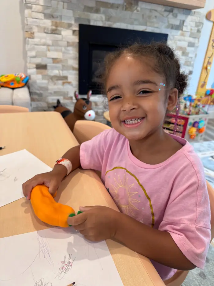 Smiling toddler joyfully playing with colorful blocks during bilingual circle time in daycare
