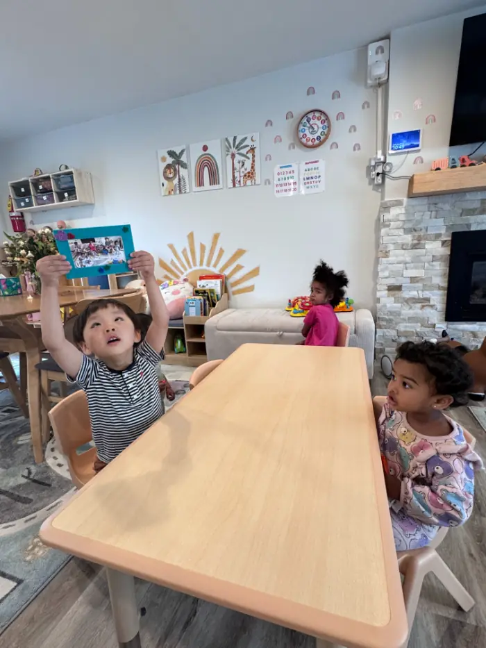 Toddler receiving sticker reward for sharing toys in daycare
