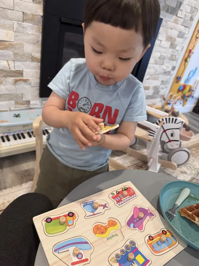 A toddler solving a wooden puzzle at KidoHeaven daycare in Bothel