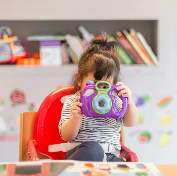 A toddler holding a toy camera up to her eye